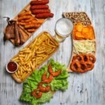 A spread of fried foods, like french fries, onion rings, and shrimp, on a wooden table. 