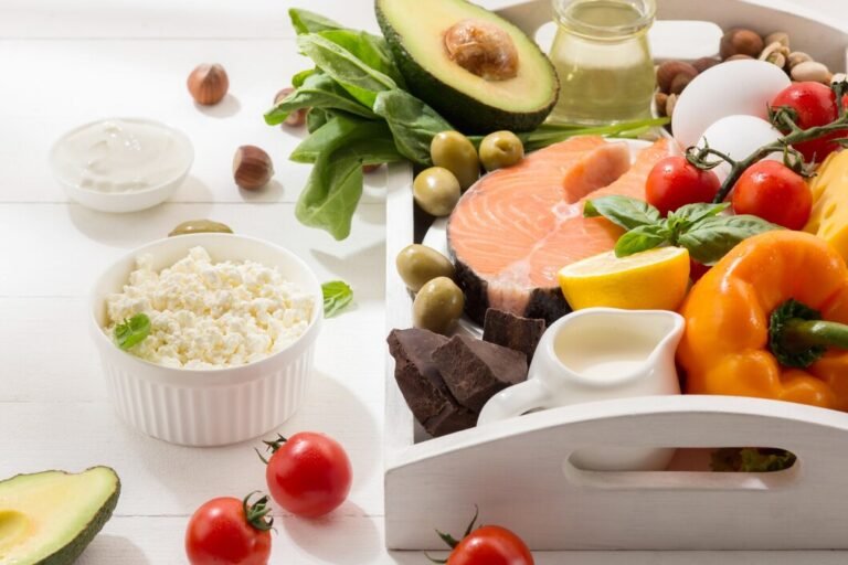 A white tray filled with food components of the Mediterranean Diet for PCOS, including salmon, avocado, cottage cheese, and dark chocolate.