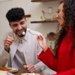 A man and woman laugh together while enjoying a meal, incorporating elements of a Mediterranean Diet.