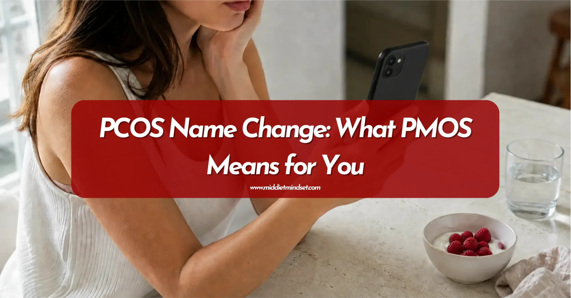 Woman reading about the PCOS name change on her smartphone while sitting at a kitchen table.