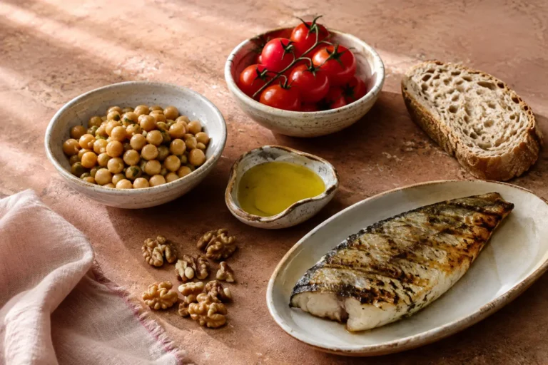 Grilled fish with chickpeas, tomatoes, whole-grain bread, walnuts, and olive oil for a Mediterranean diet vs. low-carb PCOS comparison.
